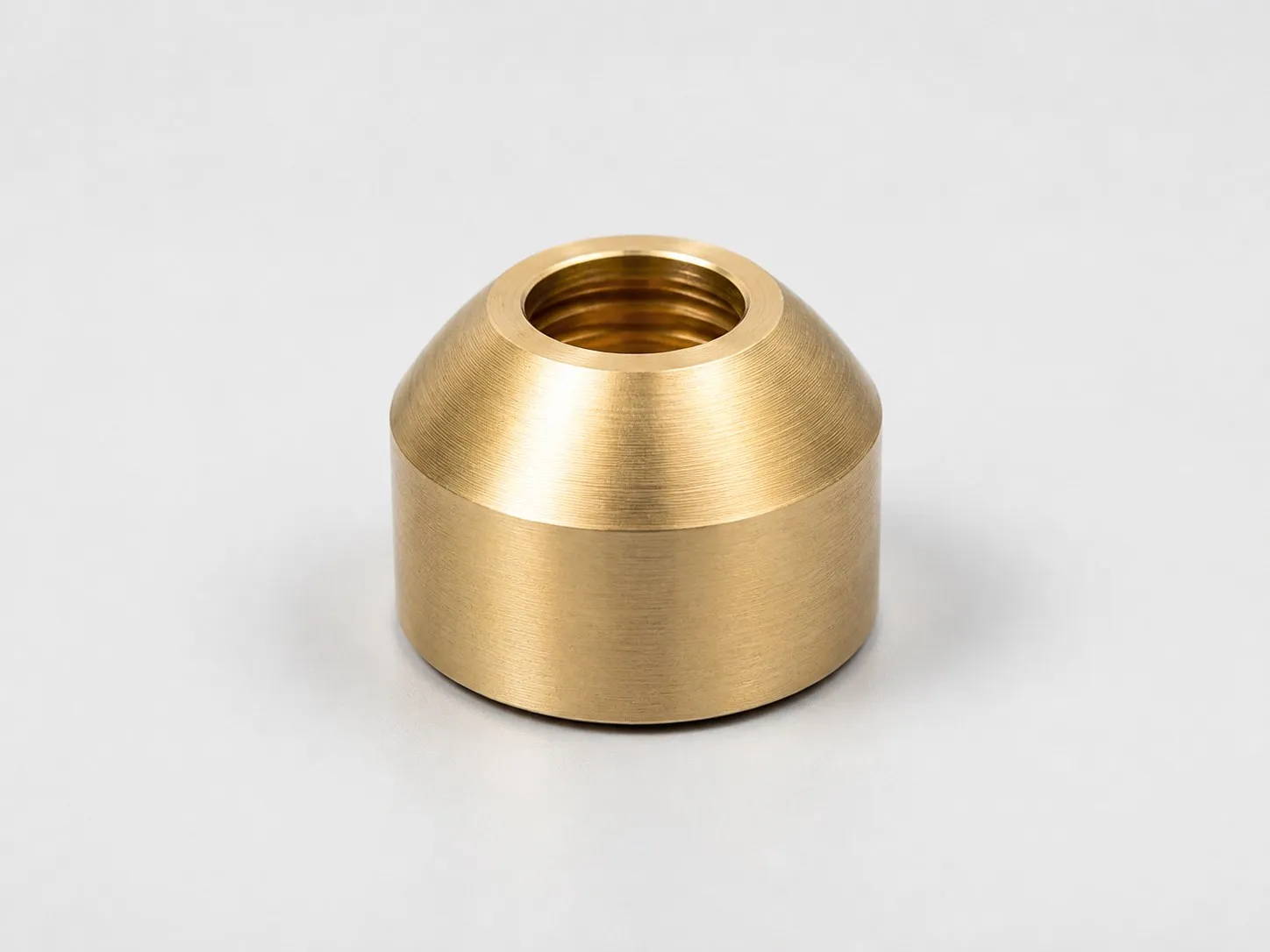 Machined bronze bushing with central threaded hole and external finish.