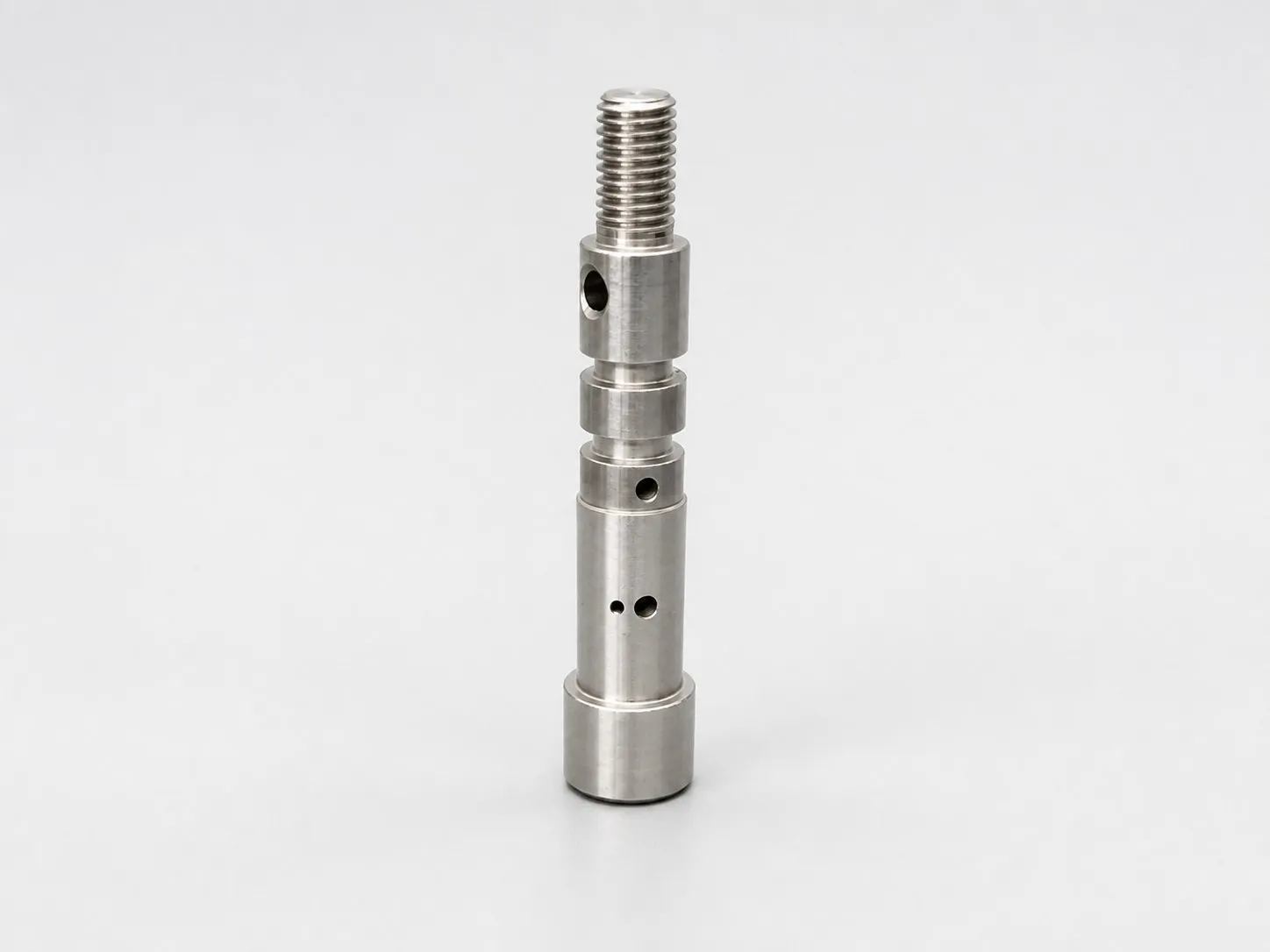 Vertical metal shaft with external thread and cross holes.