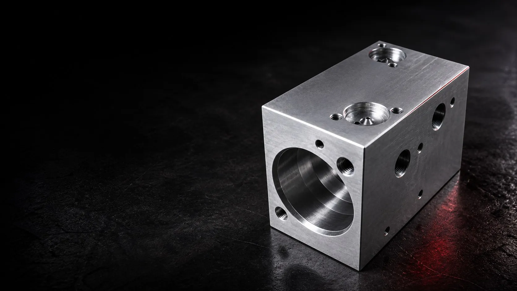 Precision-machined aluminum block with a large cavity, threaded holes, and industrial finishing.